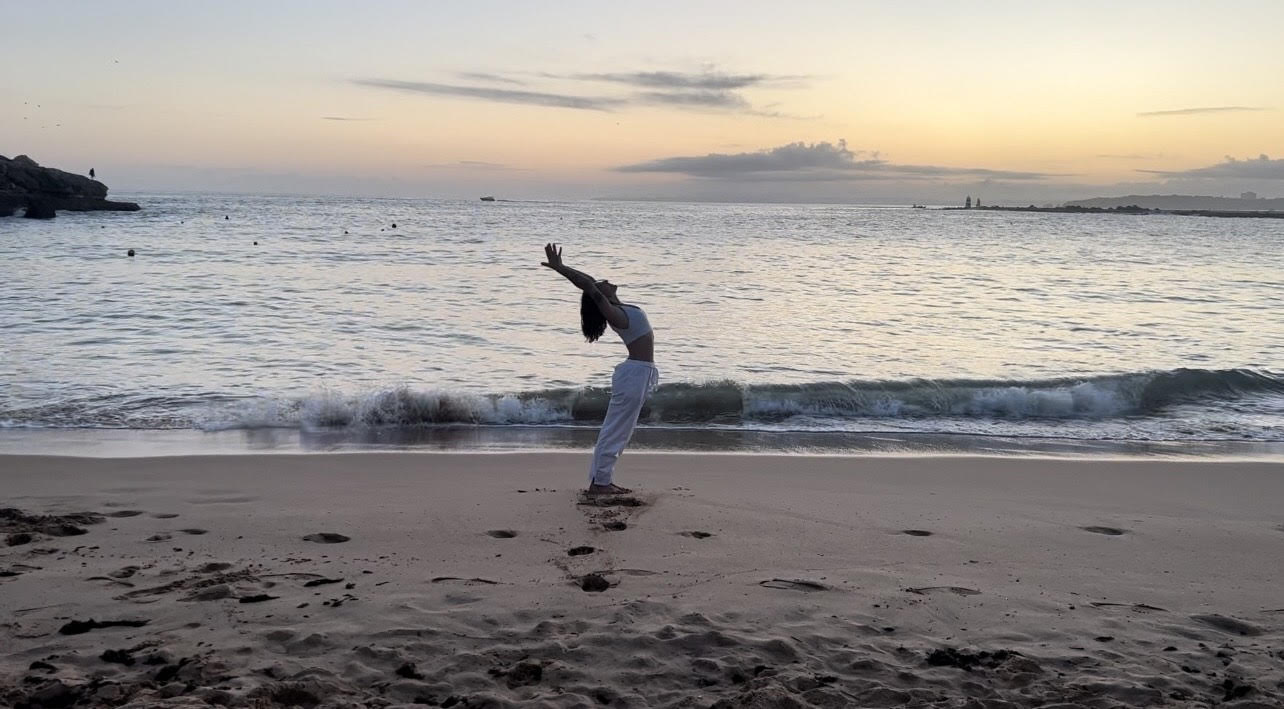 Photo d'Emma faisant une pose de yoga sur la plage pendant le coucher du soleil.