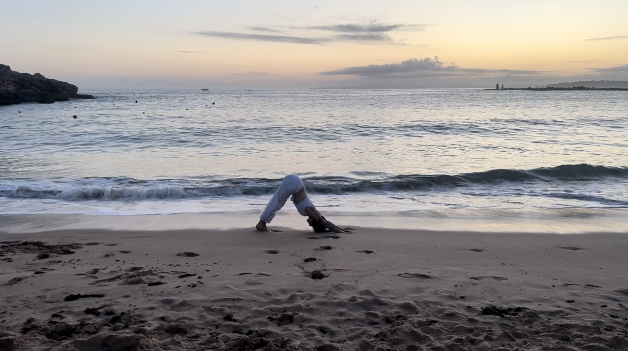 Photo d'Emma faisant une pose de yoga sur la plage pendant le coucher du soleil.