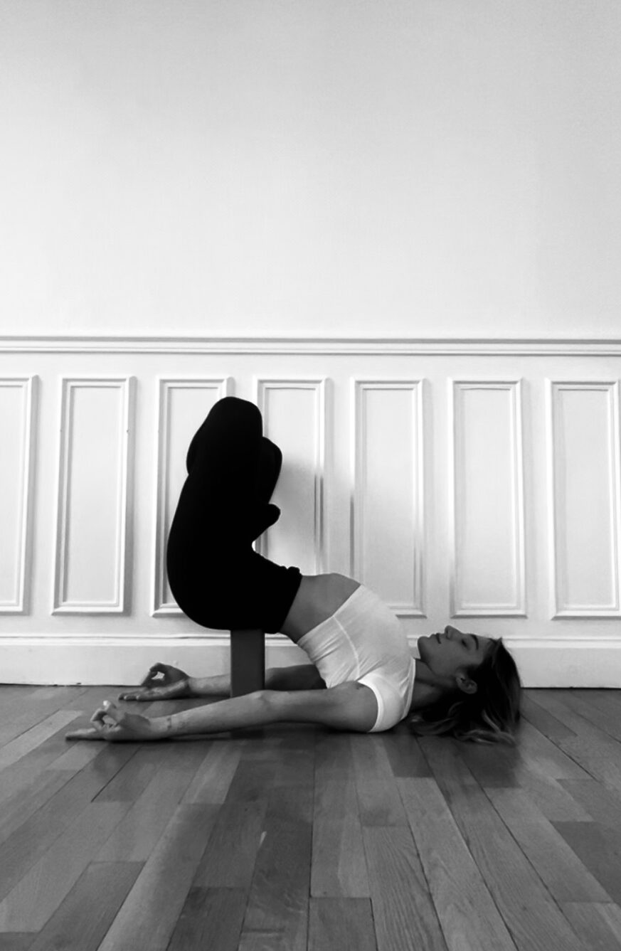 Photo en noir et blanc d'Emma faisant une pose de yoga en intérieur.